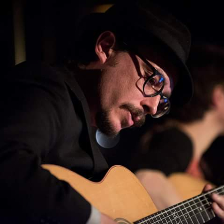 Close-up of Marc Wencelius playing acoustic guitar on stage