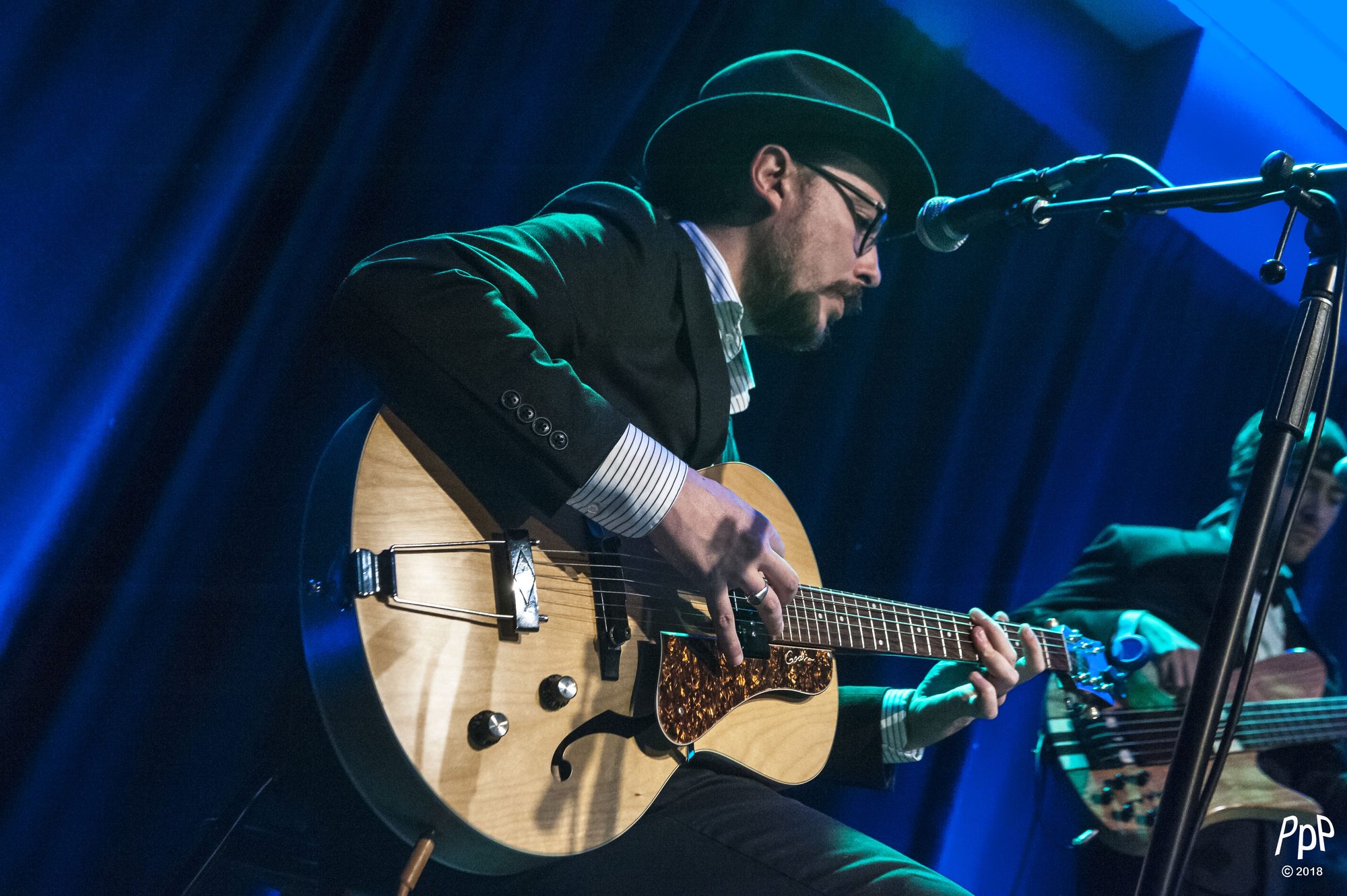 Marc Wencelius playing archtop guitar under blue stage lights, 2018