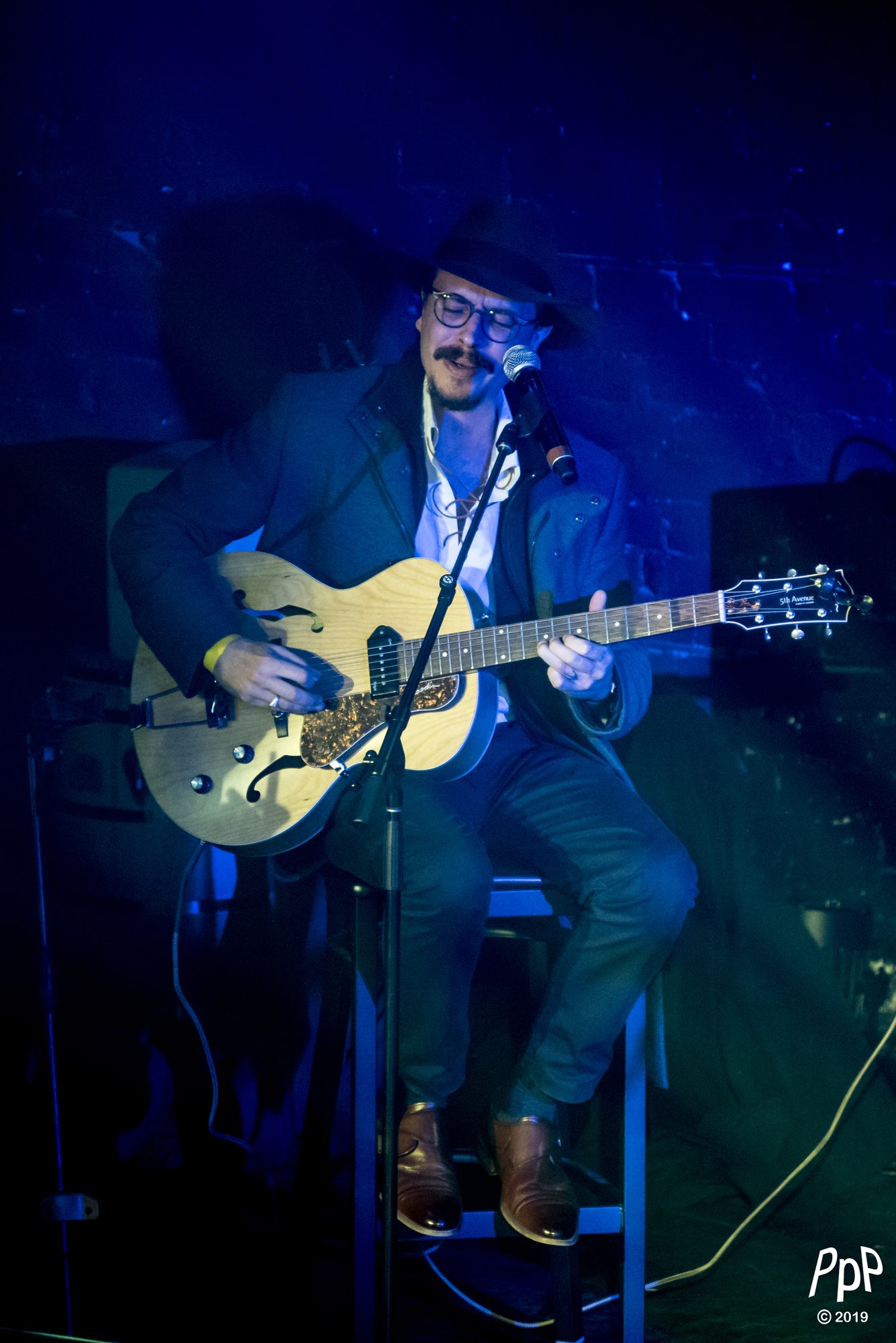 Marc Wencelius seated on stage playing archtop guitar, 2019