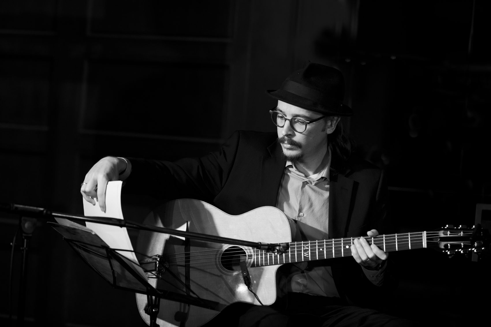 Black-and-white photo of Marc Wencelius playing guitar beside a music stand