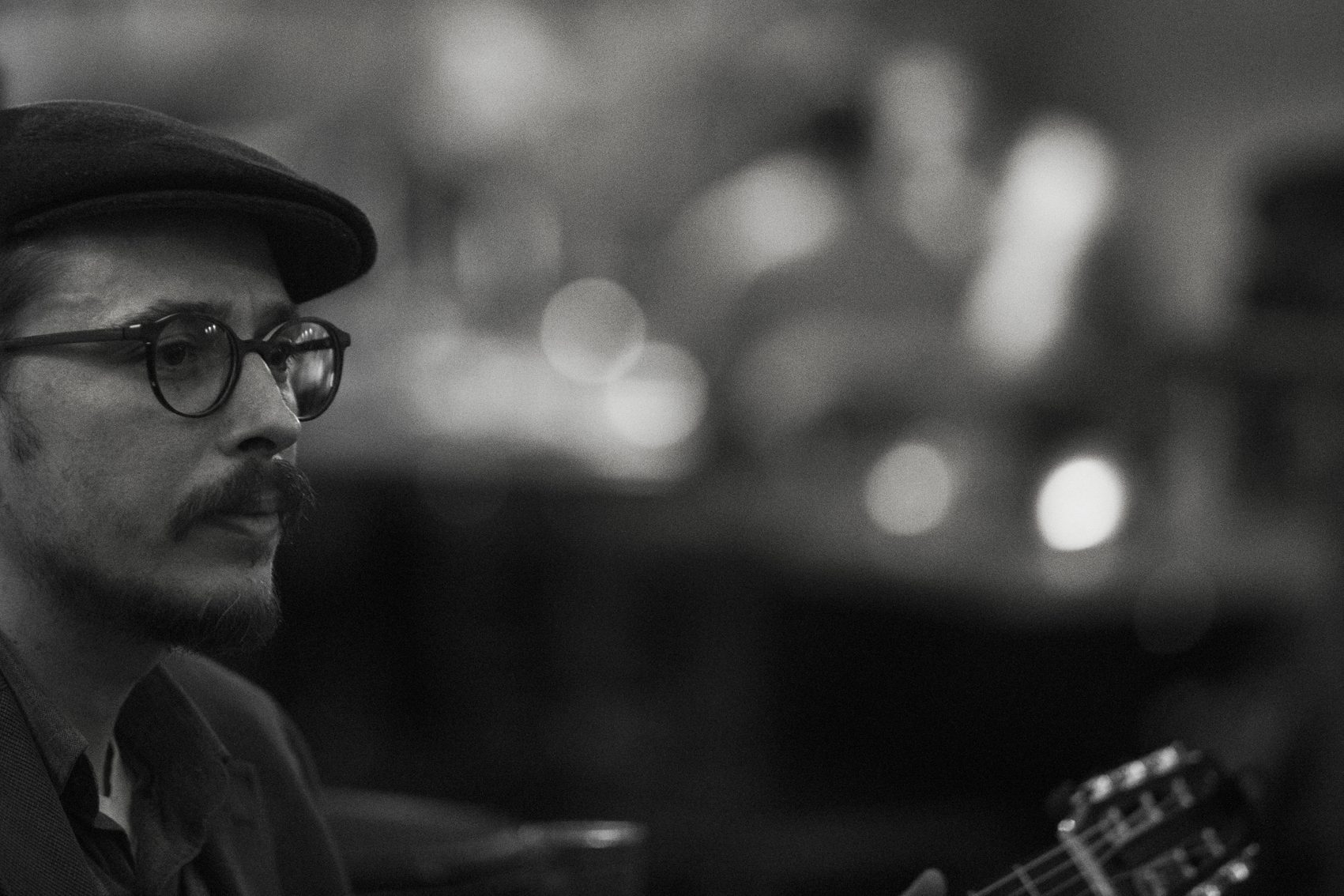 Black-and-white portrait of Marc Wencelius beside his guitar