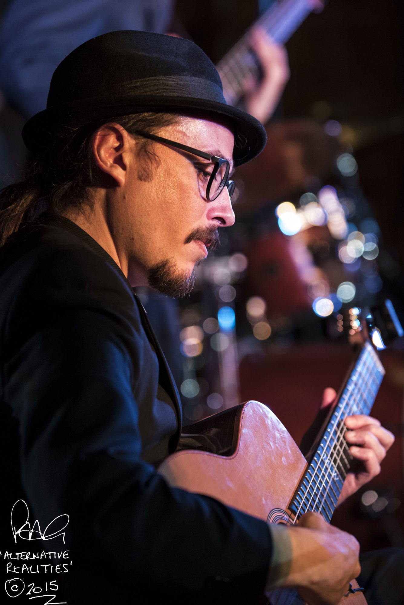 Marc Wencelius in a hat, playing guitar, 2015