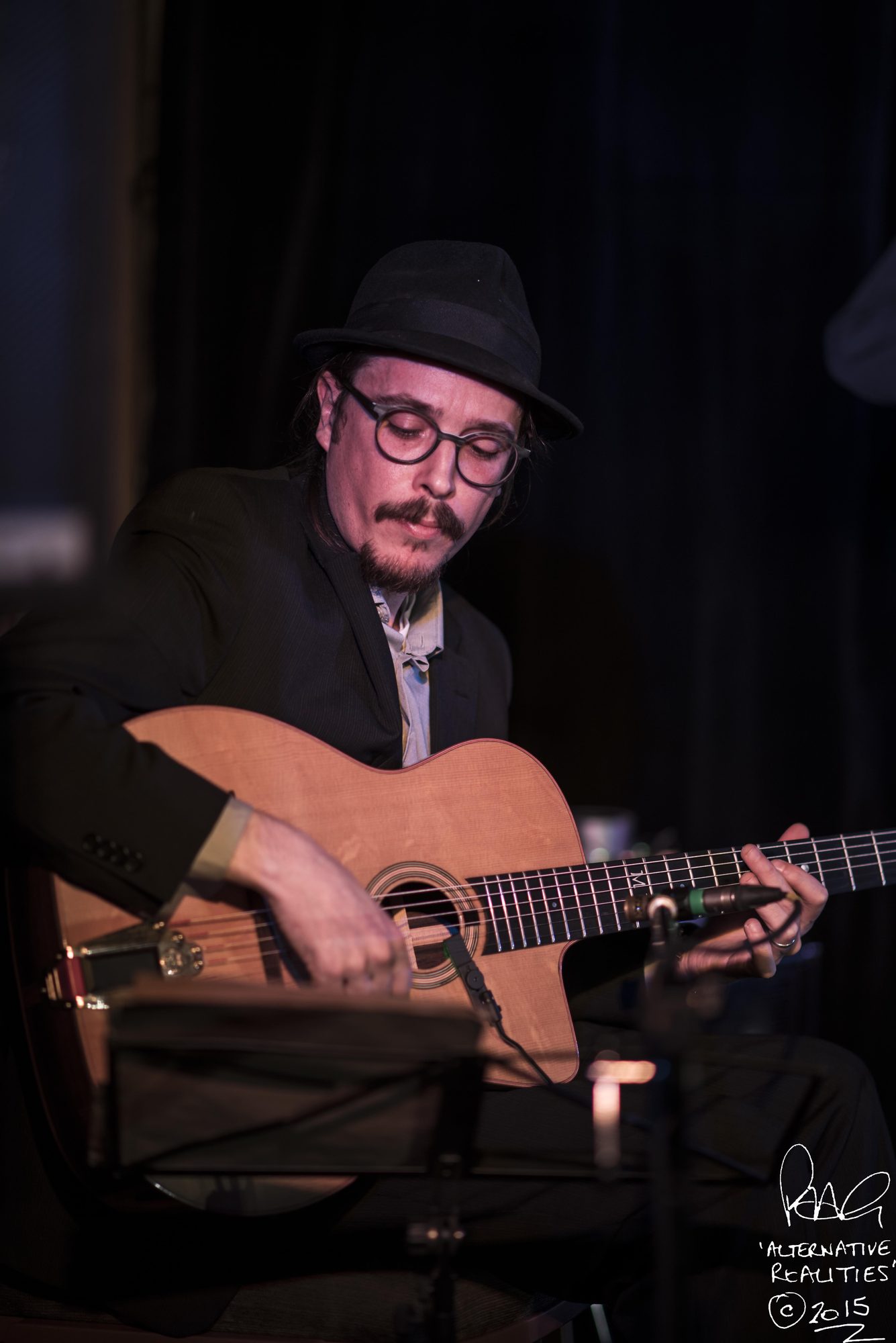 Marc Wencelius seated, playing acoustic guitar, 2015