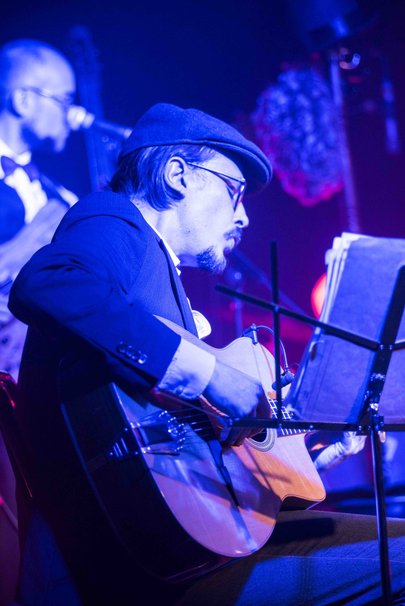 Marc Wencelius singing and playing guitar under blue stage lights