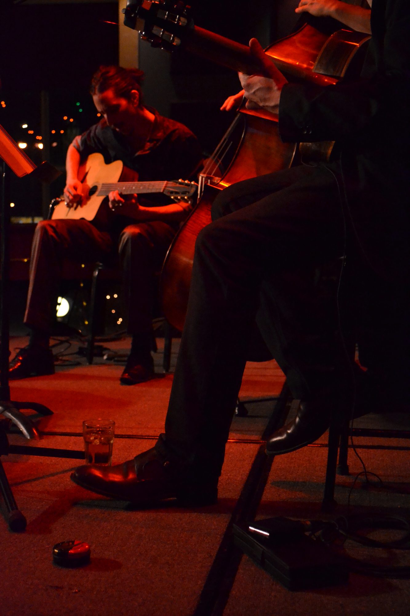 Marc Wencelius’s leg and a glass of whiskey on stage, with guitarist Quintin Bart in the background